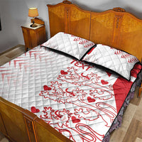 White quilt bed set with red crest, hearts, and black trim on quilted surface
