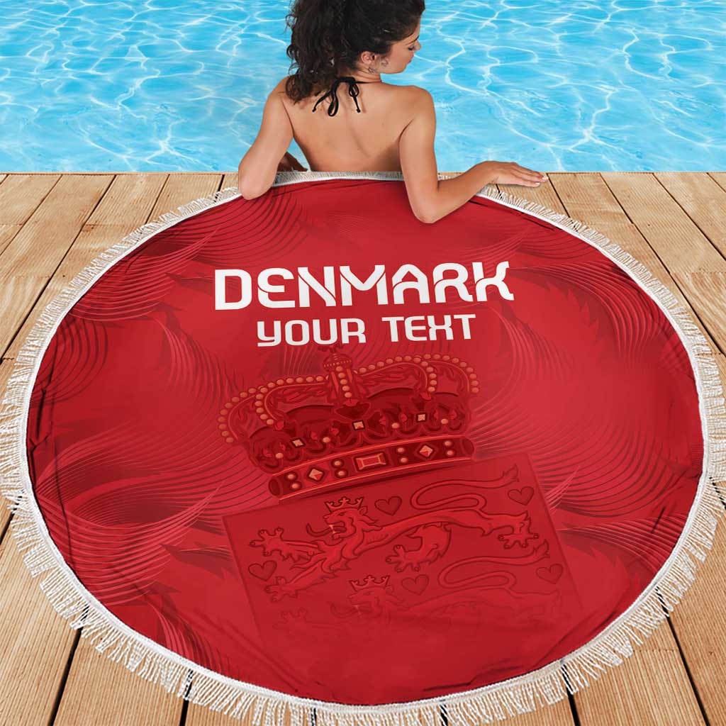 Red circular beach blanket with Denmark-themed crest print and white braided fringe edge.