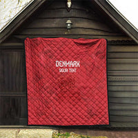 Red quilt hanging in a doorway, diamond quilting with 'DENMARK' and 'YOUR TEXT' print