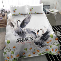 White bedding set with large gray swan print and orange daisy flowers across duvet