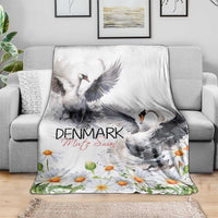 White mute swan blanket with daisies and floral border, laid across a couch