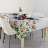 White tablecloth with orange and yellow daisy pattern and green leaves across the table.