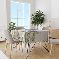 White floral tablecloth with orange-yellow daisies and green leaves, neatly draped.