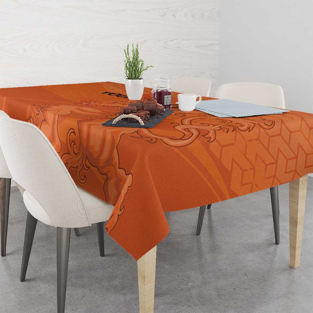 Orange football tablecloth with hex pattern and lion medallion, draped over dining table