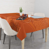 Orange football tablecloth with hex pattern and lion medallion, draped over dining table