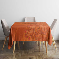 Orange football tablecloth with lion artwork, covering a square dining table