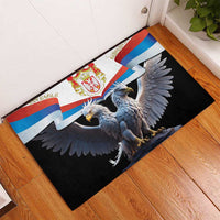 Black rubber doormat with Serbia flag and double-headed eagle, laid on wood floor