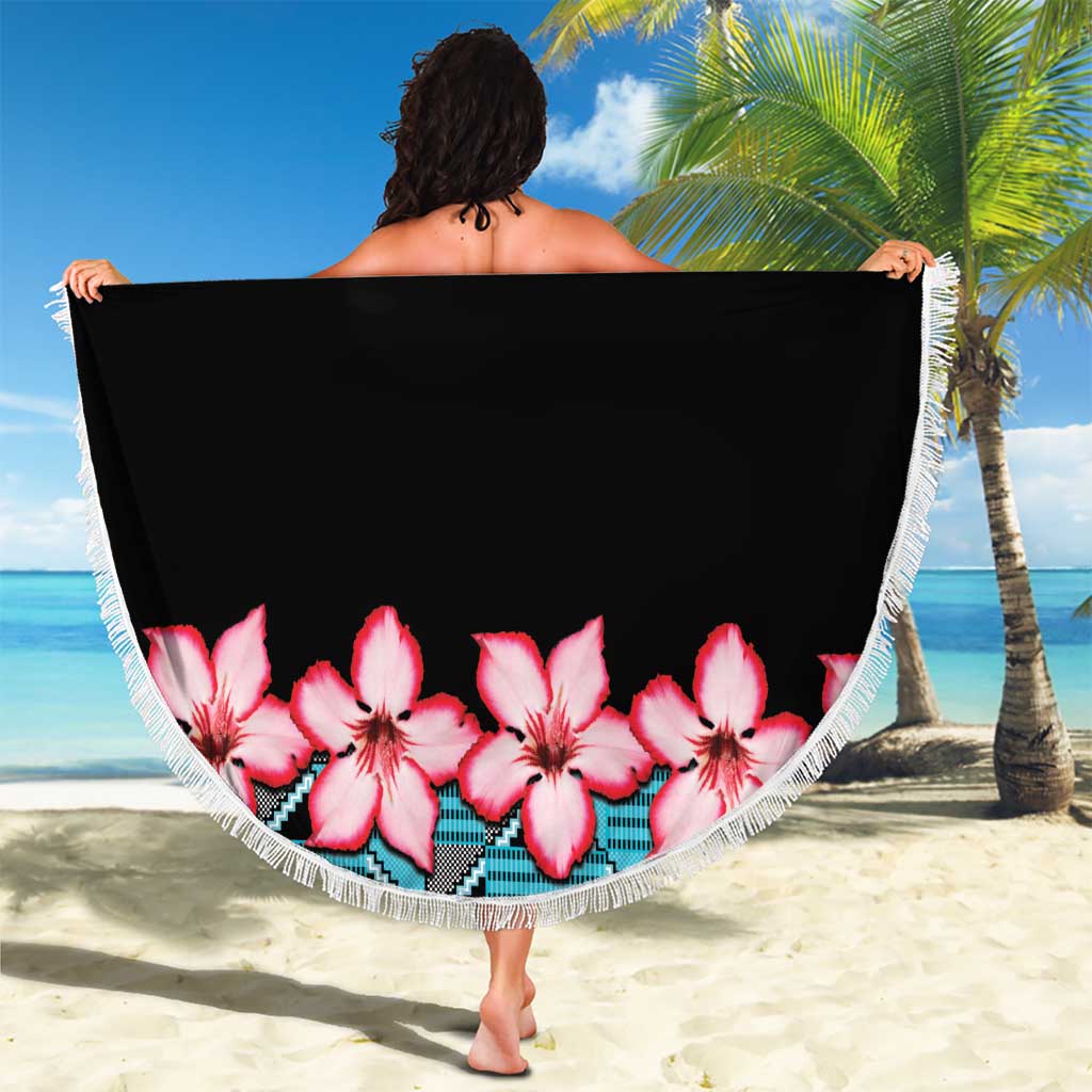 Round beach blanket with white fringe; black body with pink hibiscus band along bottom edge