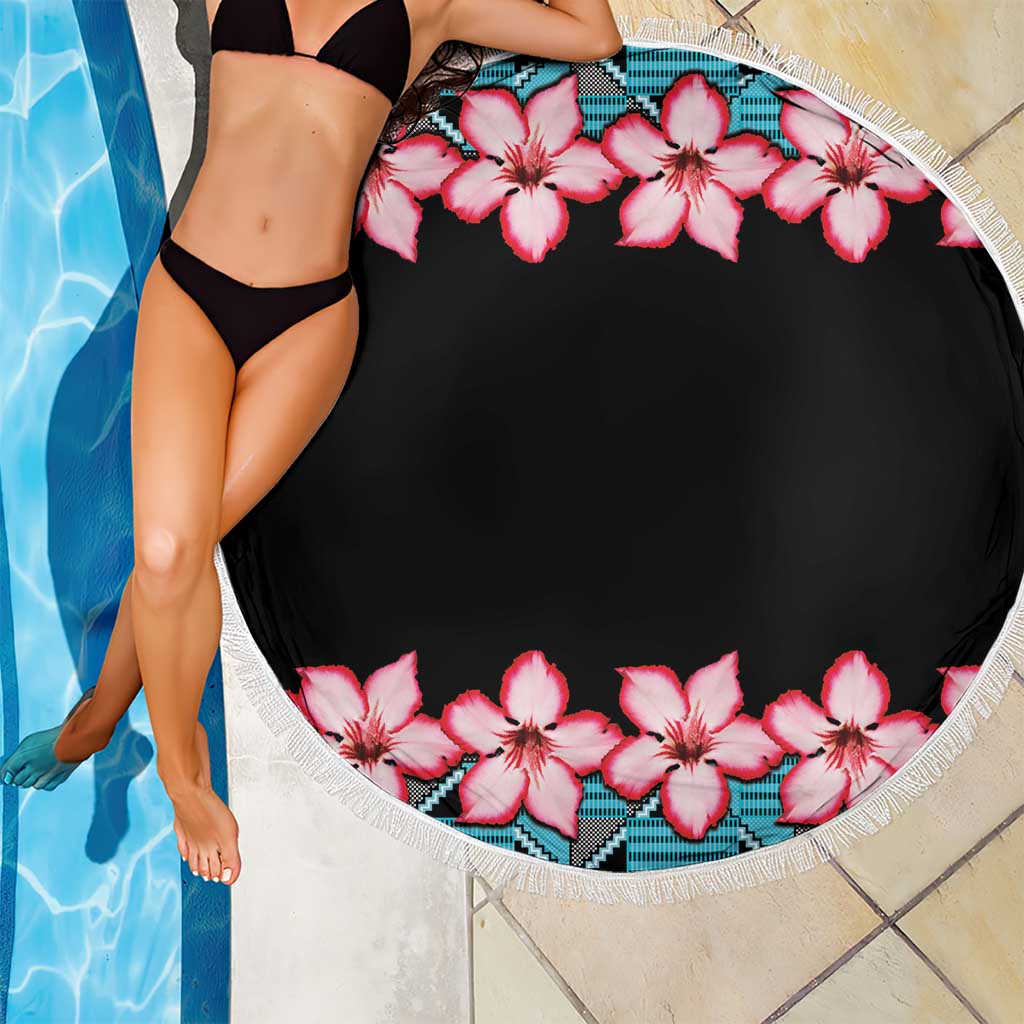 Round beach blanket with white fringe; black center with pink hibiscus flowers and teal pattern border