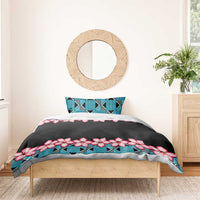 Black duvet with turquoise geometric band and pink hibiscus flowers on bed