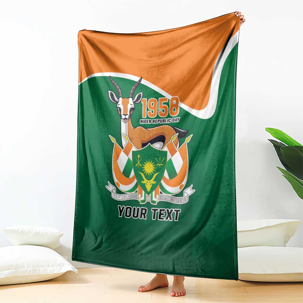 Personalized blanket draped on floor, green with orange corner and emblem with 'YOUR TEXT'