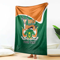 Personalized blanket draped on floor, green with orange corner and emblem with 'YOUR TEXT'