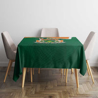 Green tablecloth with crest and “YOUR TEXT” print centered on small dining table