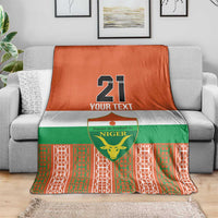 Football blanket in orange, green, and white with Niger emblem and number 21 on couch