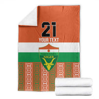 Folded orange, green, and white football blanket with Niger crest and custom number 21