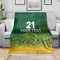 Custom cricket blanket draped over a sofa; dark green top, gold bottom, “21 YOUR TEXT”.