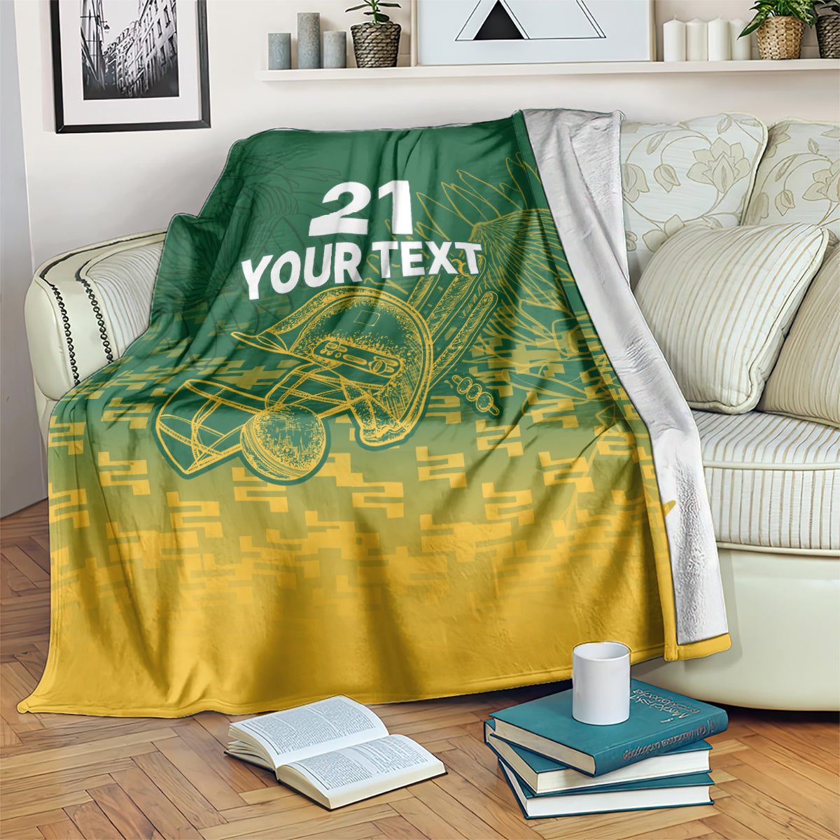 Custom cricket blanket on couch with “21 YOUR TEXT” and cricket bat emblem; dark green and gold.