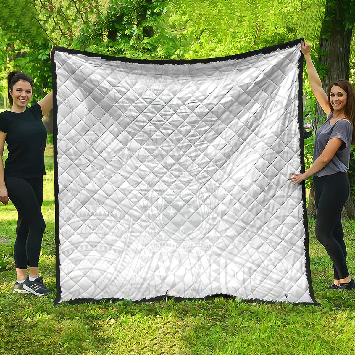 White quilt with diamond quilting, rectangular shape, and black border, held outdoors.