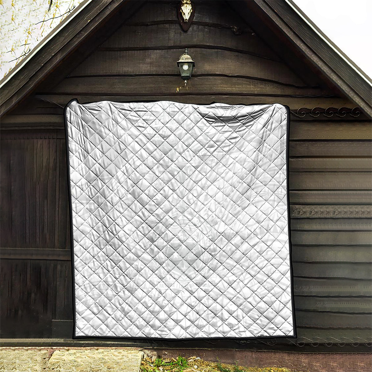 White quilt with diamond quilting and black border hanging in arched doorway.
