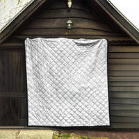 White quilt with diamond quilting and black border hanging in arched doorway.