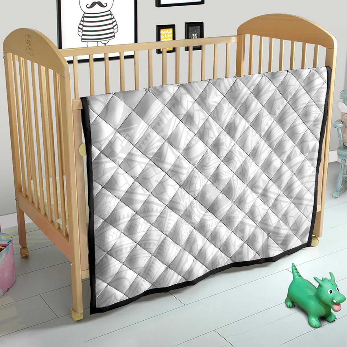 White children's quilt with diamond quilting and black border on a wooden toddler bed.