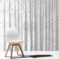 White patterned window curtain panel with star and geometric motifs, draped behind chair