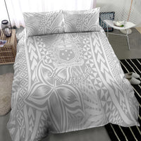 White bedding set featuring Polynesian crest medallion, leaf design, and triangle geometric print; two pillows