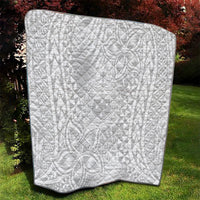 White quilt with black binding, full view with repeating geometric Polynesian design