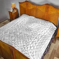 White quilt with black edge binding on a bed, showing tropical Polynesian print
