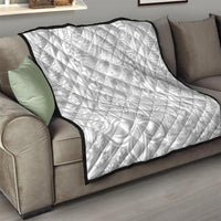 White quilt with black edge binding on a couch, quilted texture with Polynesian motifs