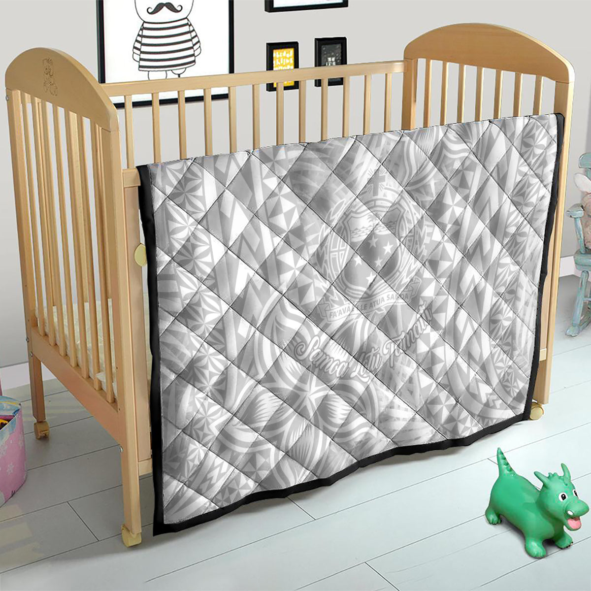 White baby quilt with black border in a crib, featuring tropical Polynesian-style pattern