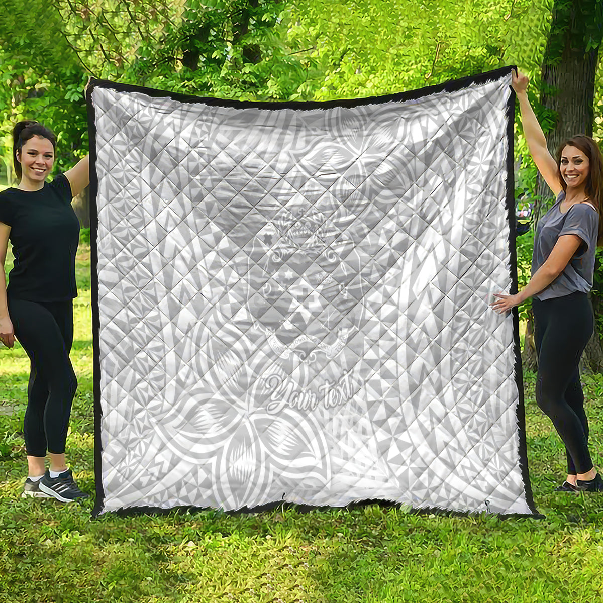 White quilt blanket with black border, tropical polynesian-style print and text