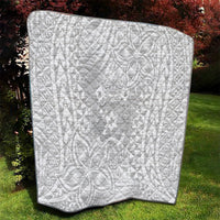 White quilt blanket with black trim, quilted texture, polynesian-inspired motifs