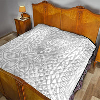 White quilt blanket with black trim and tropical polynesian-style pattern on bed