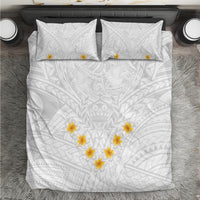 White bedding set with white-on-white tribal leaf pattern, yellow plumeria on duvet and two pillows