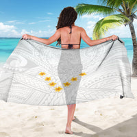 White sarong featuring tribal motifs and yellow plumeria flowers, worn as wrap