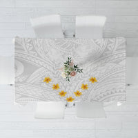 White tablecloth with gray geometric pattern and yellow plumeria flowers at center
