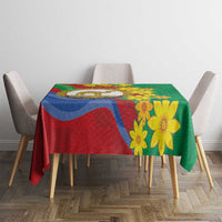 Green and red tablecloth with yellow floral print and multicolor emblem