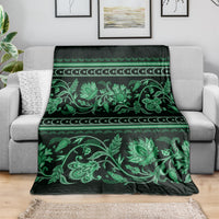 Green floral ornamental throw blanket folded over a sofa