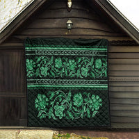 Green quilt hung on wall with quilted diamond texture and ornate floral border