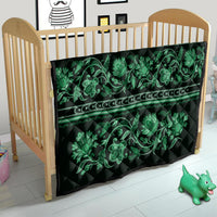 Green quilt laid in a wooden crib with teal floral vine pattern and border stripe