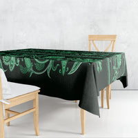 Green traditional tablecloth with flowing floral border, draped over table