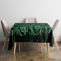 Green traditional tablecloth with ornate border pattern, neatly laid on table