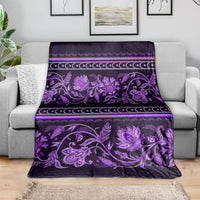 Violet floral ornament throw blanket draped on a sofa, with striped border