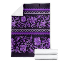 Violet traditional ornament throw blanket with floral pattern and border, folded with towels