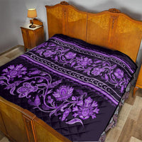 Violet quilt covering a bed, with purple floral buta design, border stripes, and quilting