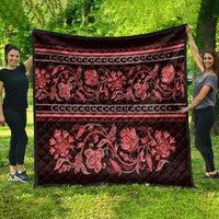 Red quilt laid flat outdoors with large floral paisley motif and banded borders
