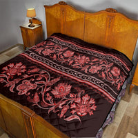 Red quilt spread on a bed with floral paisley design and horizontal stripe borders
