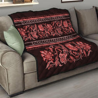 Red quilt draped on a sofa with floral paisley print and striped decorative bands