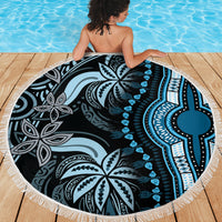 Round beach blanket with blue and black mandala print and white fringe on wood deck